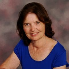 A woman in blue shirt smiling for the camera.