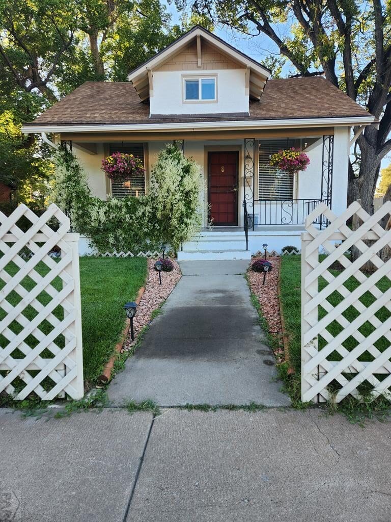 White house with a walkway and fence.